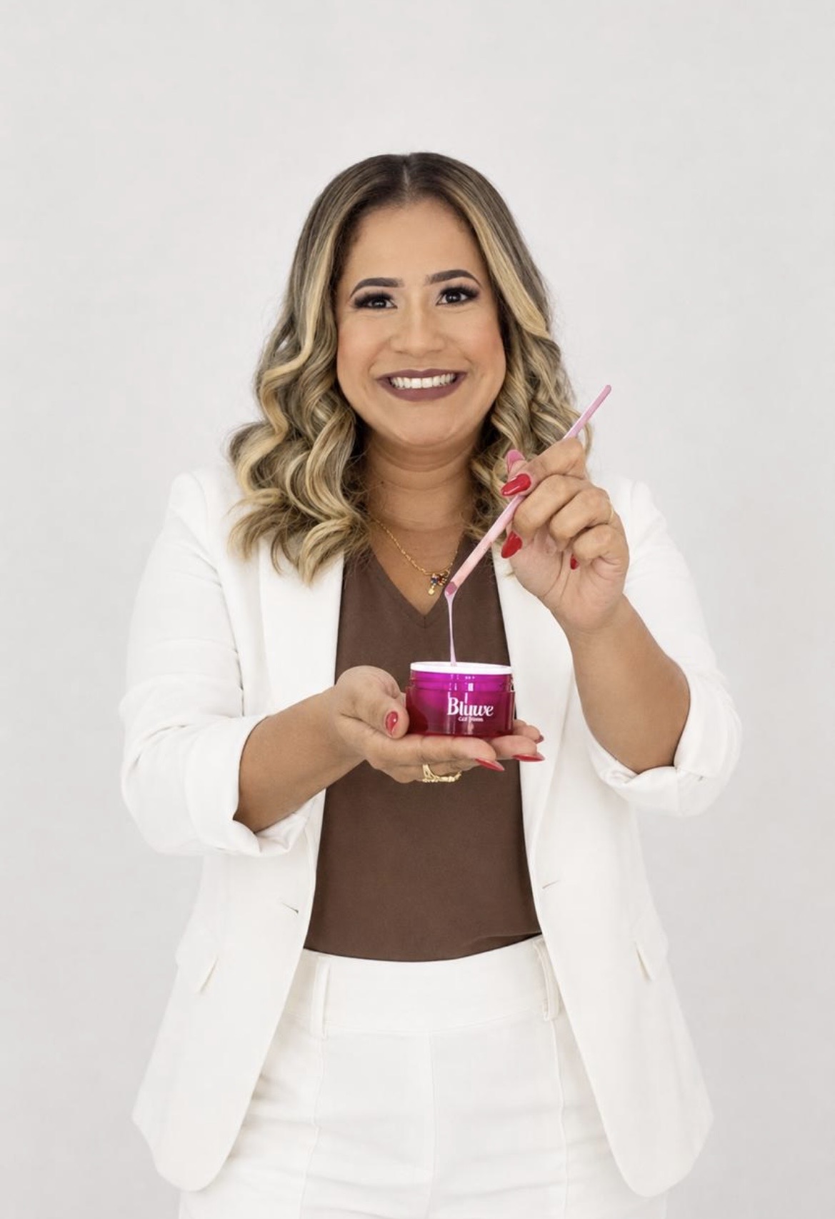 Jeni Souza, nail designer, segurando um pote de gel de construção